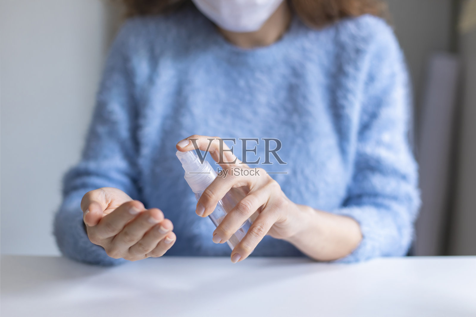戴口罩的妇女用消毒剂喷雾清洁双手照片摄影图片
