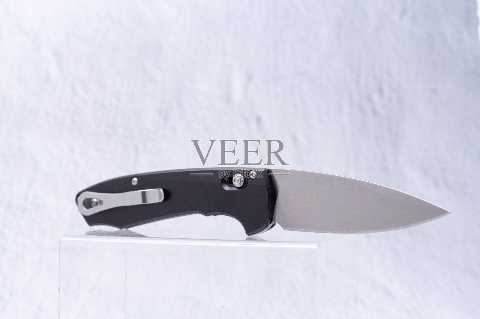 刀刃光亮，刀柄上有夹子的刀。把刀放在陈列柜的塑料架子上。照片摄影图片