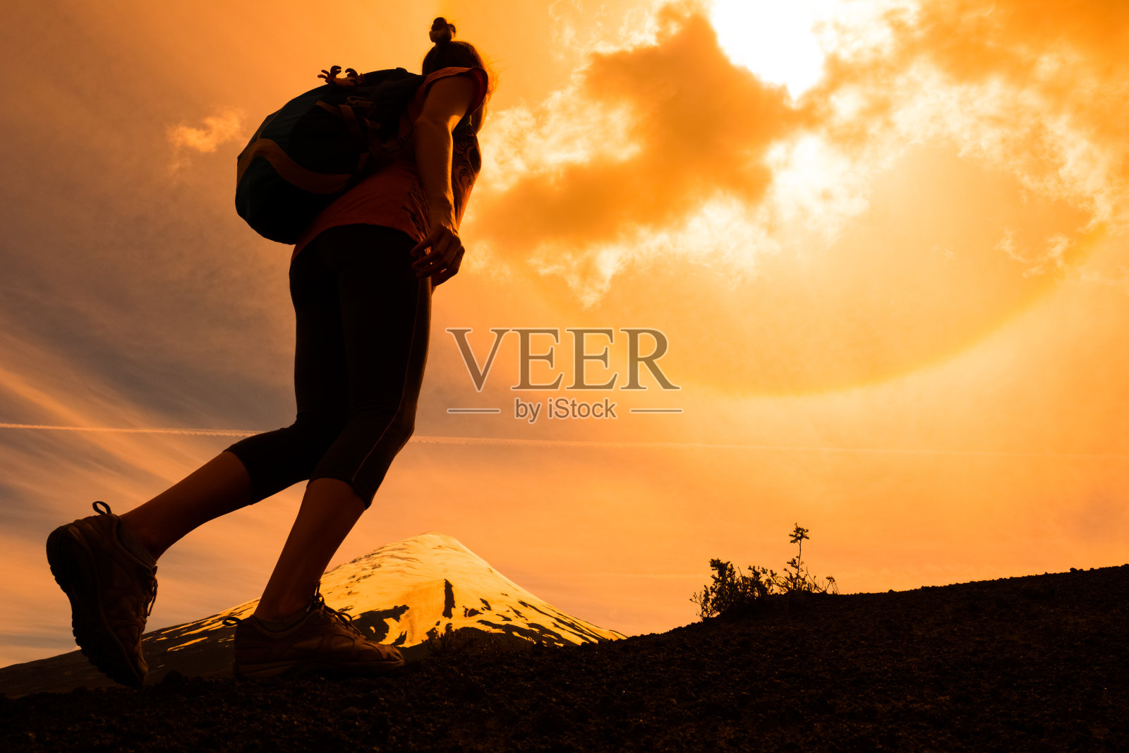 一个年轻的徒步旅行者走在荒芜的小径上，背景是白雪覆盖的山峰照片摄影图片