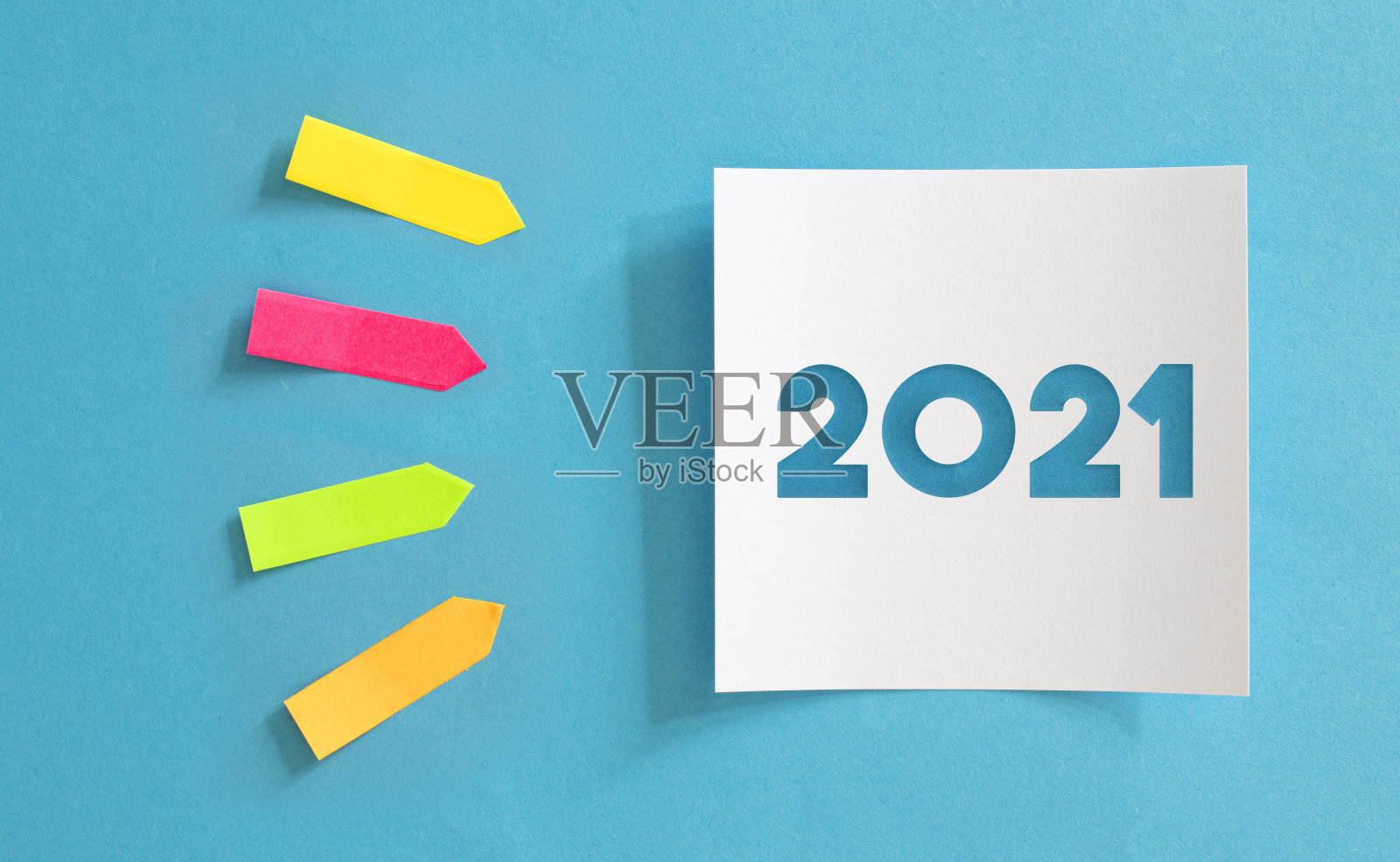 2021蓝色背景的纸与便利贴。彩色的粘纸是箭头状的指向。照片摄影图片