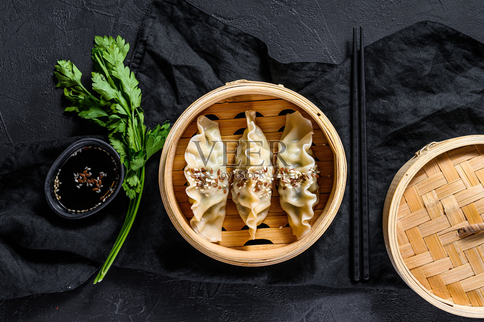 传统竹蒸笼里的韩国饺子。前视图。乡村的老式黑色背景照片摄影图片