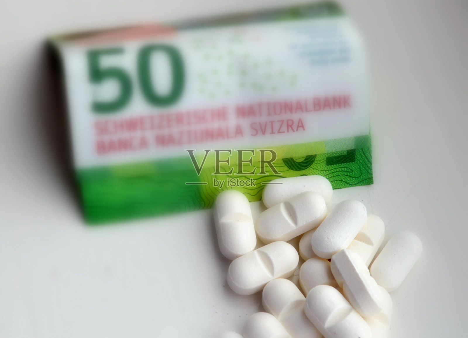 一堆药丸和瑞士钞票。照片摄影图片
