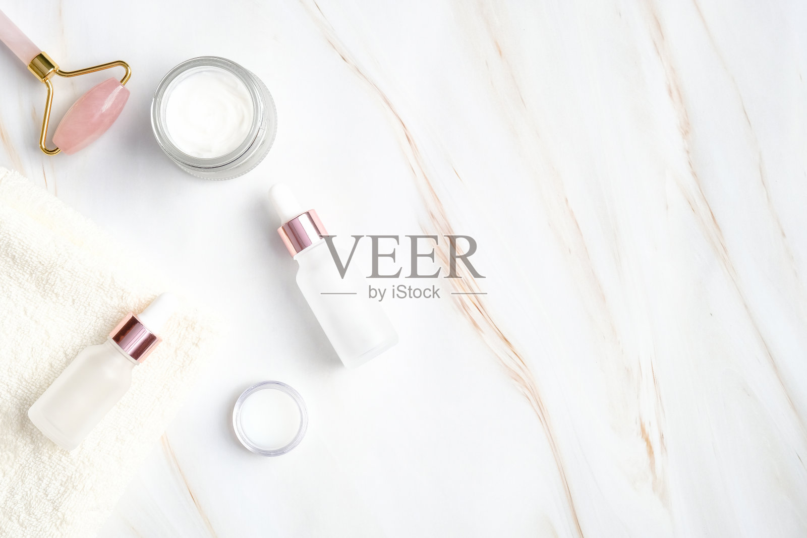 SPA天然化妆品大理石背景。平躺，俯视图有机身体霜，瓶子与血清乳液，脸部辊和毛巾。护肤美容理念。照片摄影图片