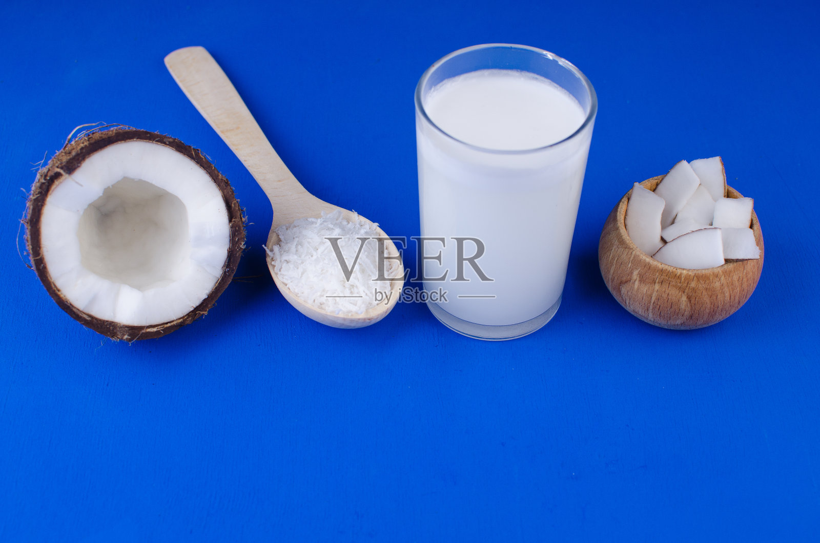 天然椰奶，椰屑，椰片在蓝色背景上。健康食品的概念。照片摄影图片