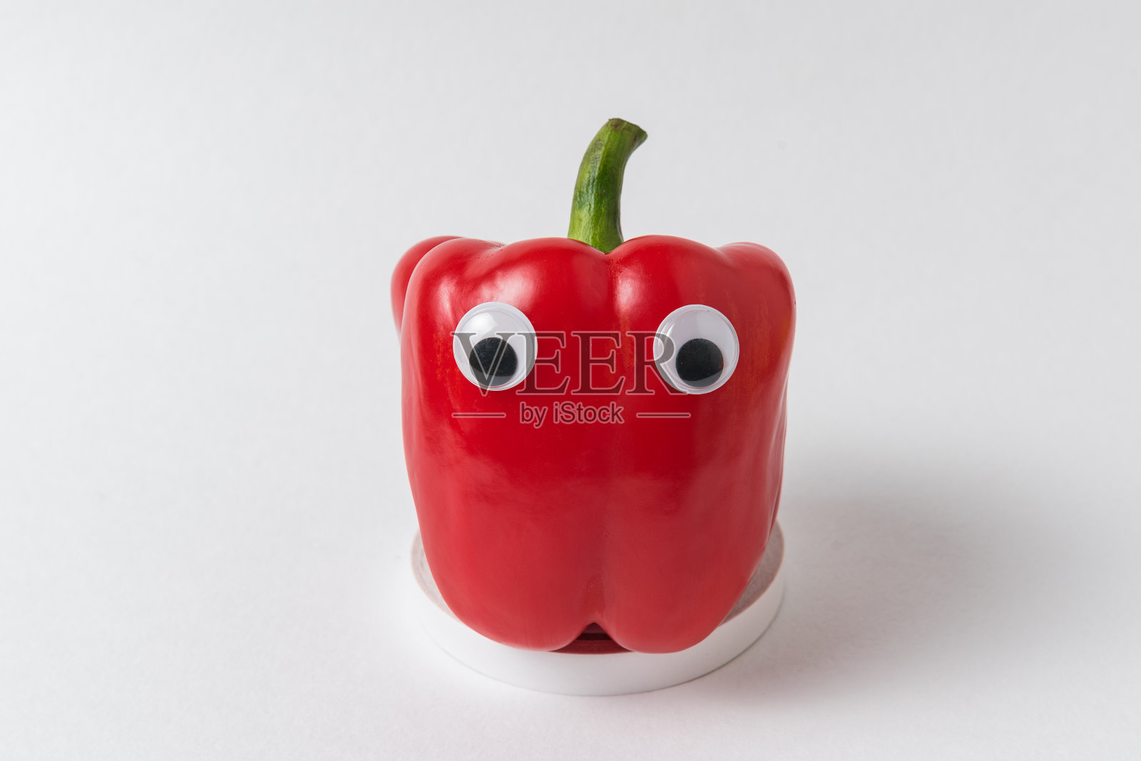 生红辣椒和谷歌眼睛在白色的背景。搞笑小辣椒照片摄影图片