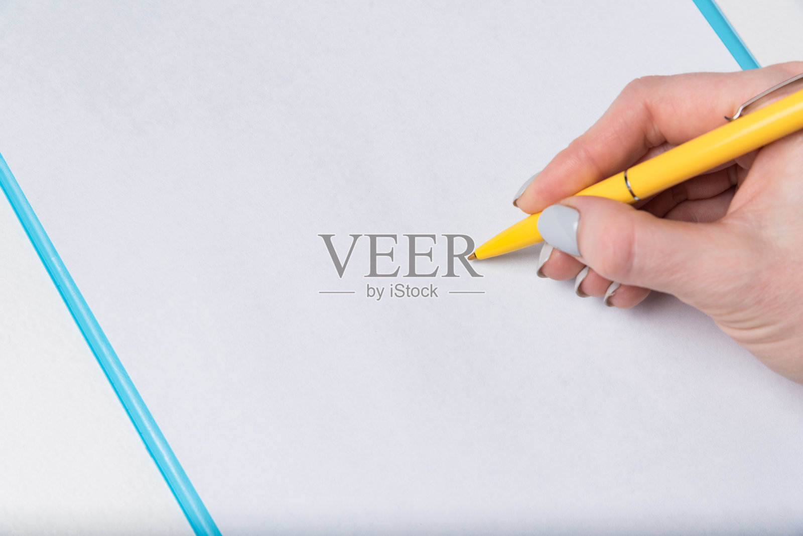 女性的手拿着笔在一张白纸上。女人在纸上签名。近距离照片摄影图片