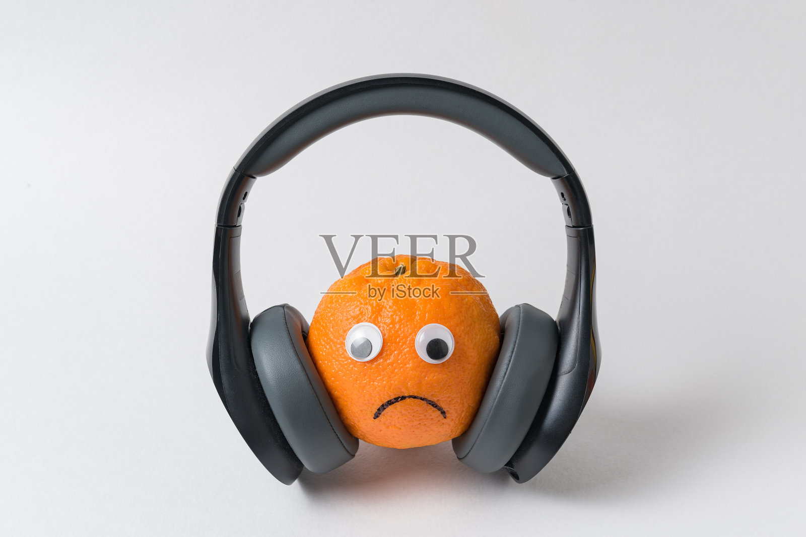 橙色的，带着大大的耳机的悲伤表情。太多噪音概念照片摄影图片