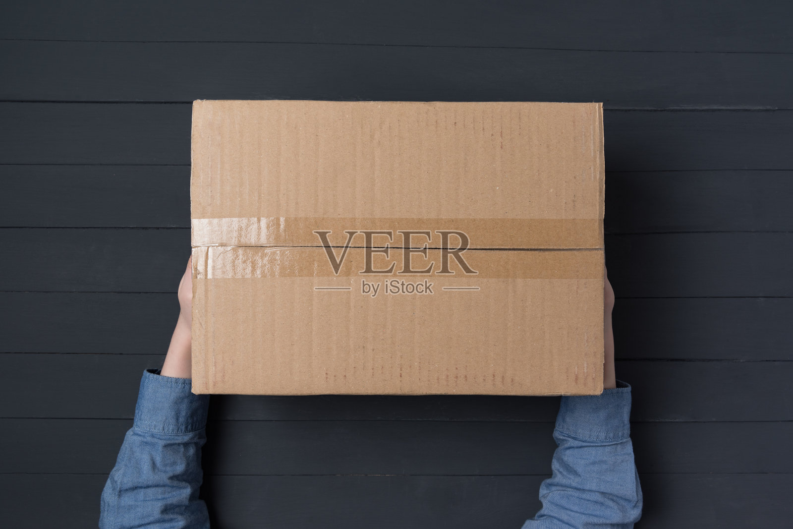 孩子的手拿着大纸板箱。送货上门。俯视图照片摄影图片