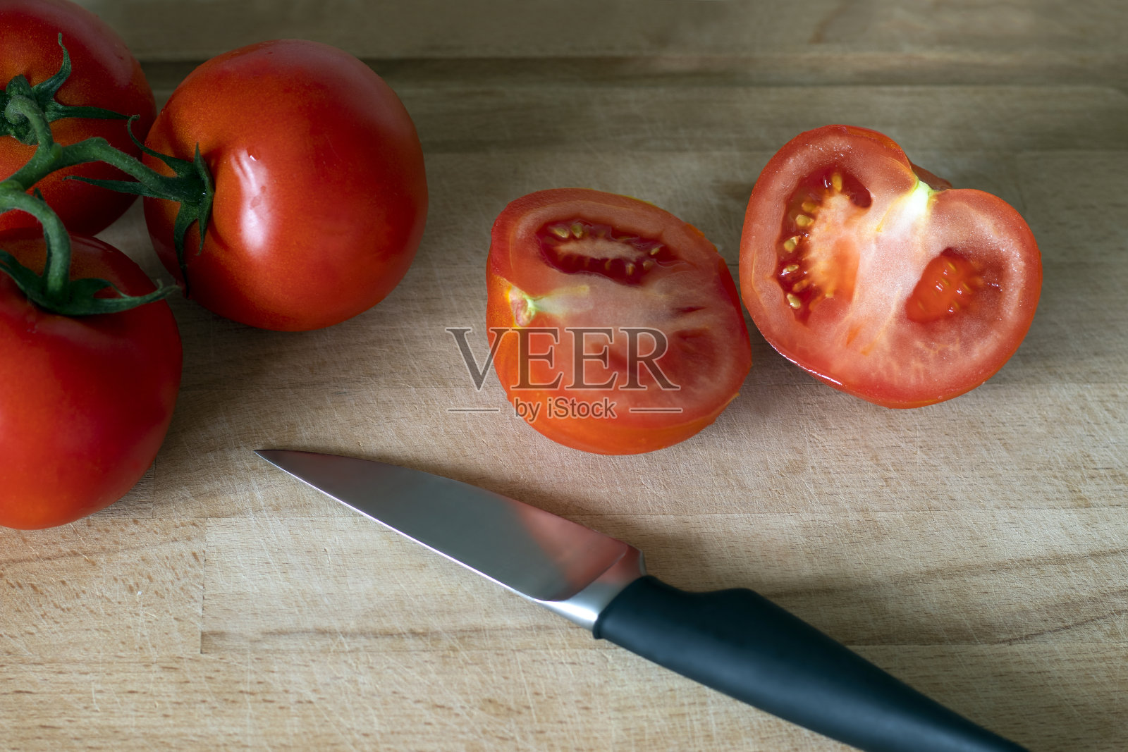 用刀在砧板上把西红柿支起来，然后切一个西红柿照片摄影图片