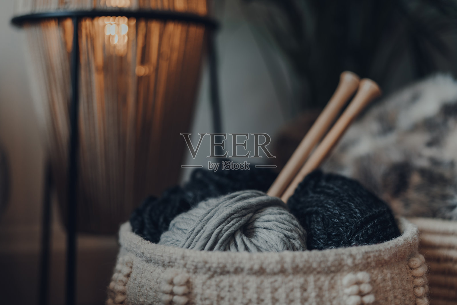 纱线球在一个篮子里，用大的木制编织针，家里的内部。照片摄影图片