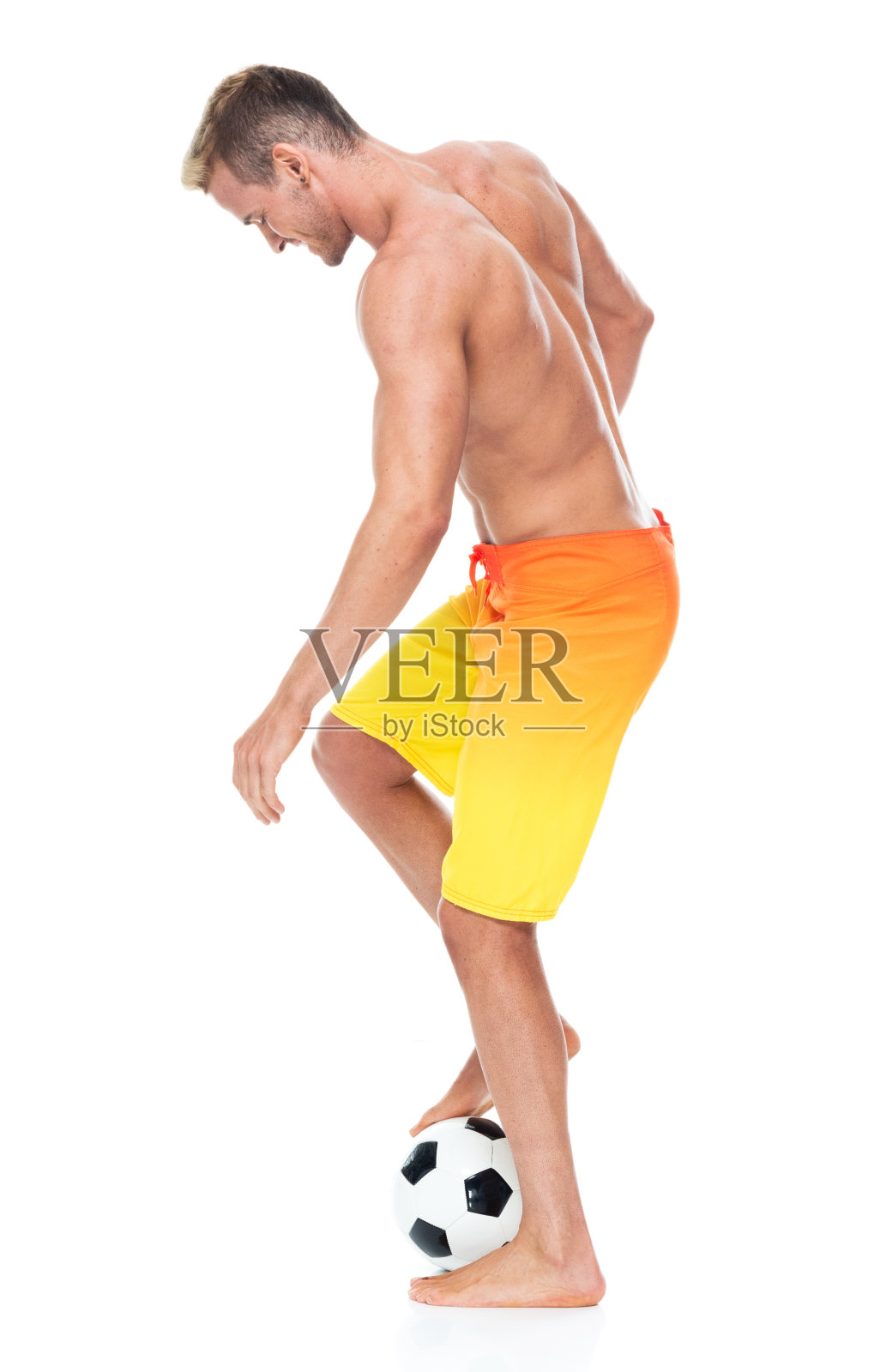 白人年轻男子足球运动员踢在前面的白色背景穿着板短裤和持有足球照片摄影图片