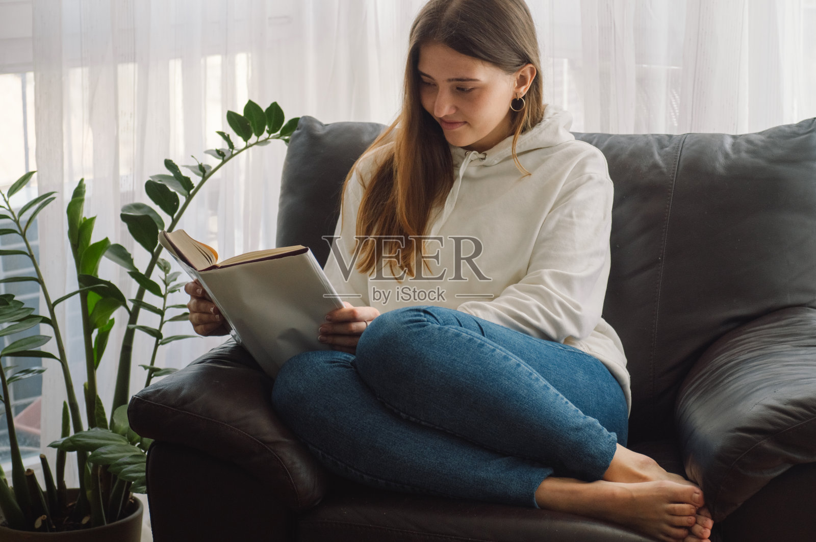 美丽的年轻女子正在家里看书。思考的女孩在读重要的书。照片摄影图片