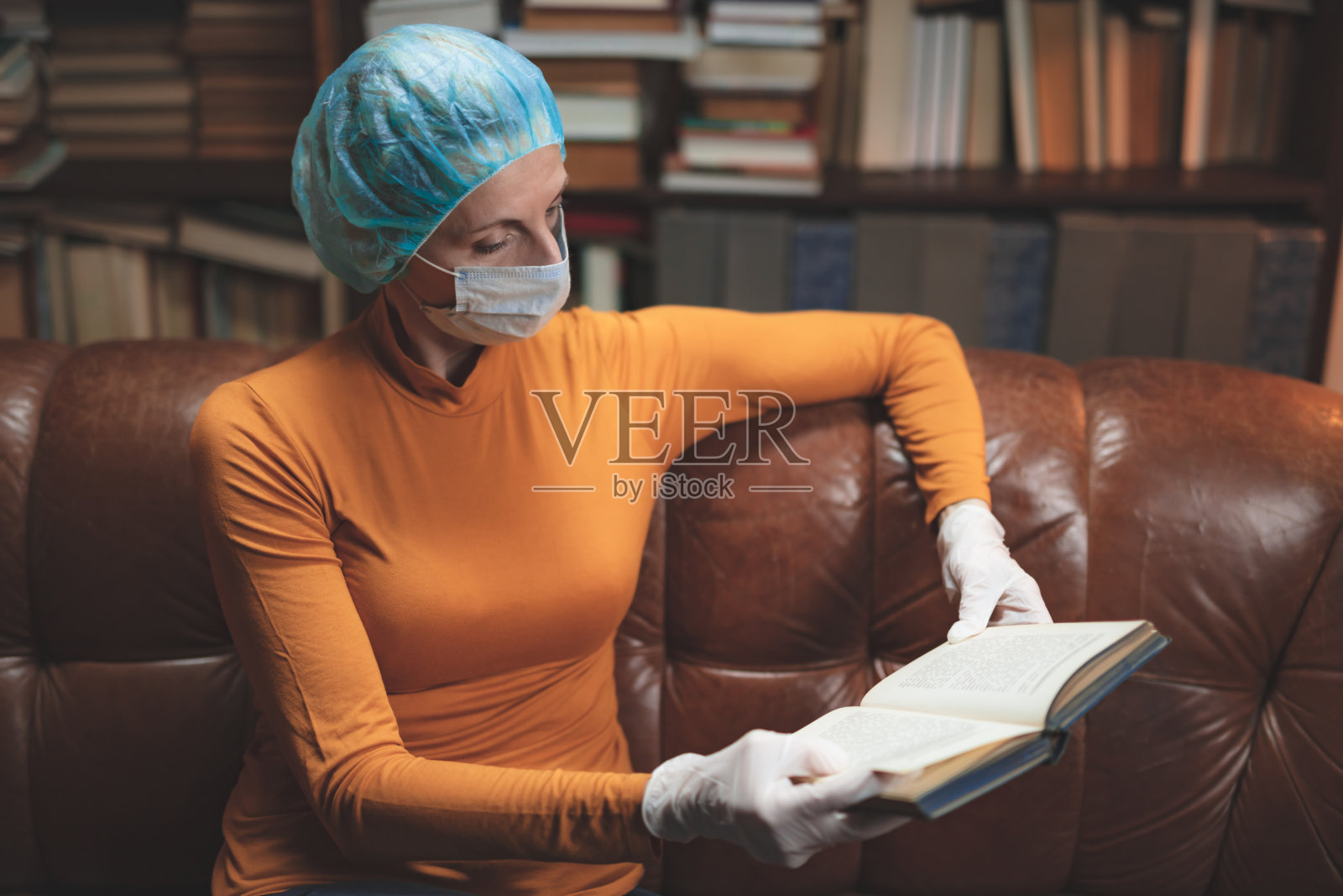 戴防护防毒口罩在家看书或隔离的妇女。照片摄影图片