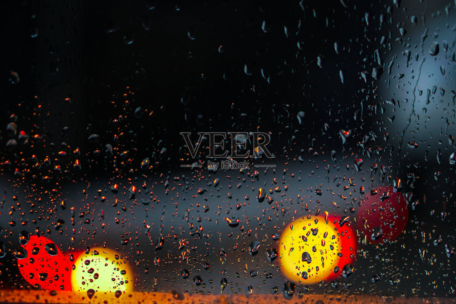 窗户俯瞰着下雨的街道。阴沉的傍晚，从街道看出去。落在玻璃上和车里的散焦。设计库存背景照片摄影图片