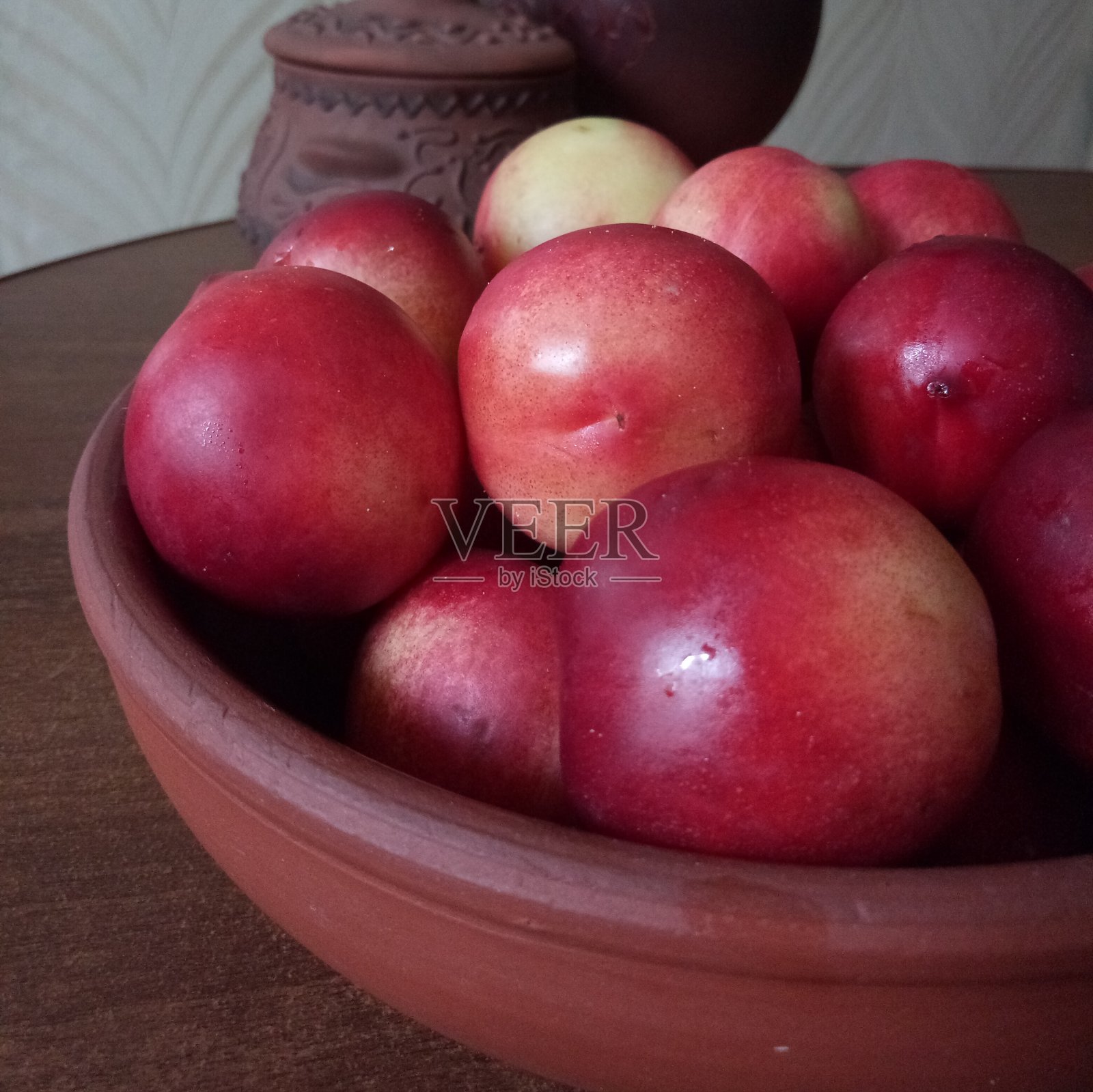 新鲜的油桃在粘土盘上，深色和木制的背景照片摄影图片