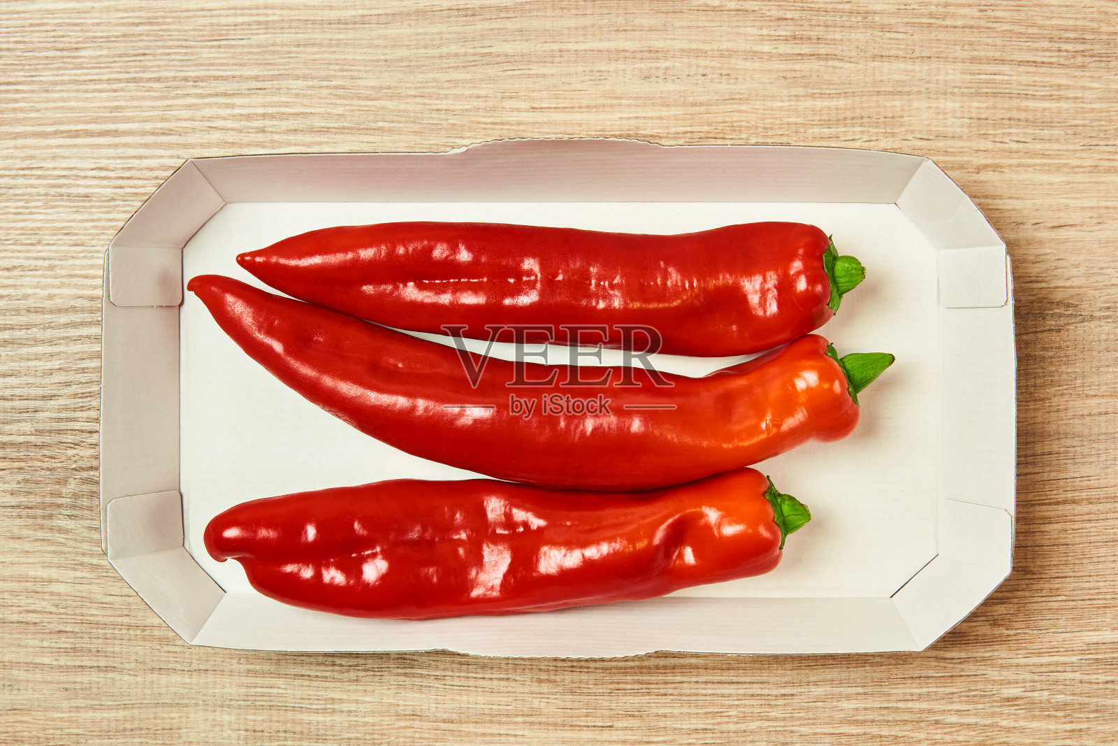 桌上的纸板托盘里放着三粒甜椒照片摄影图片