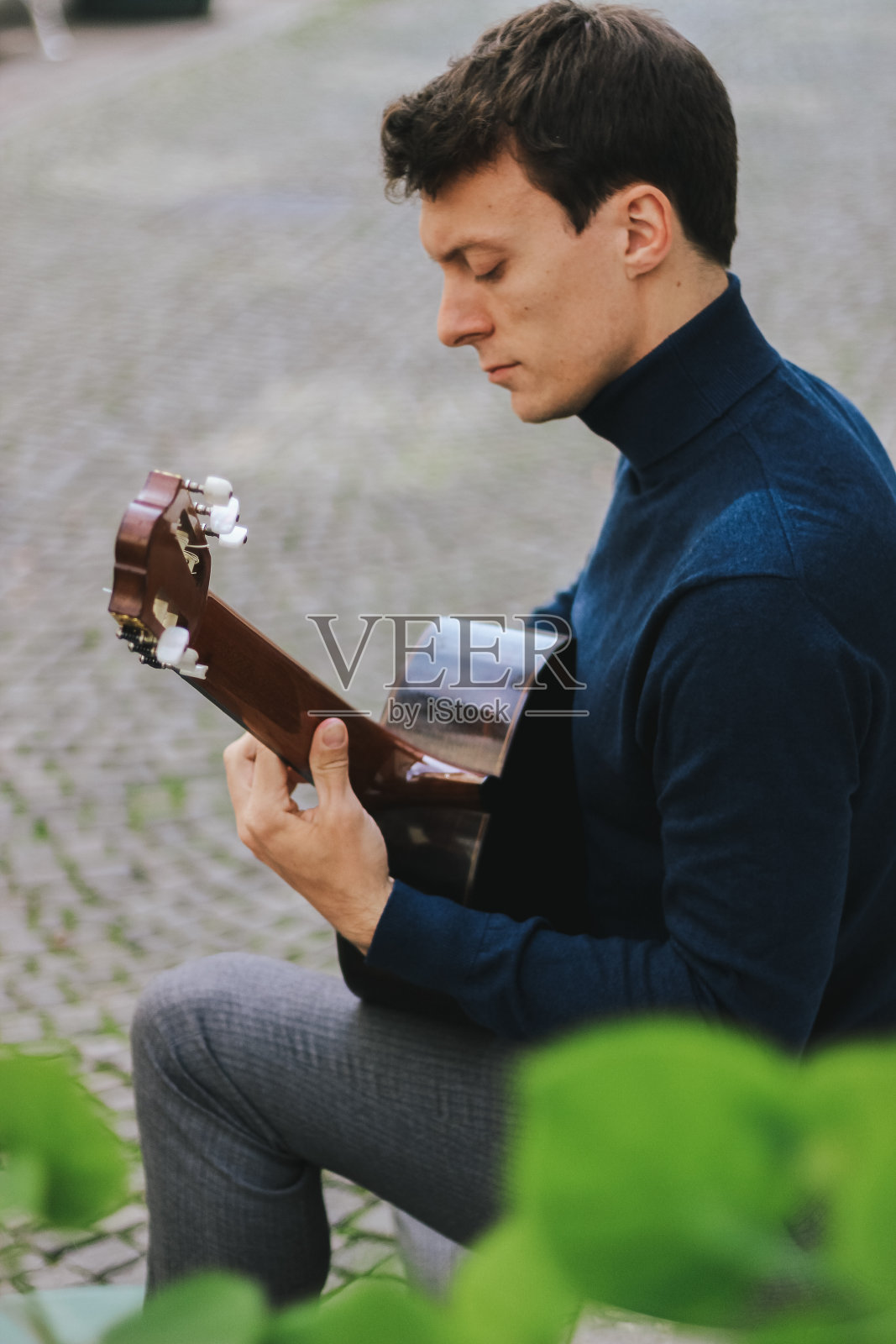 一个年轻人在外面弹吉他照片摄影图片