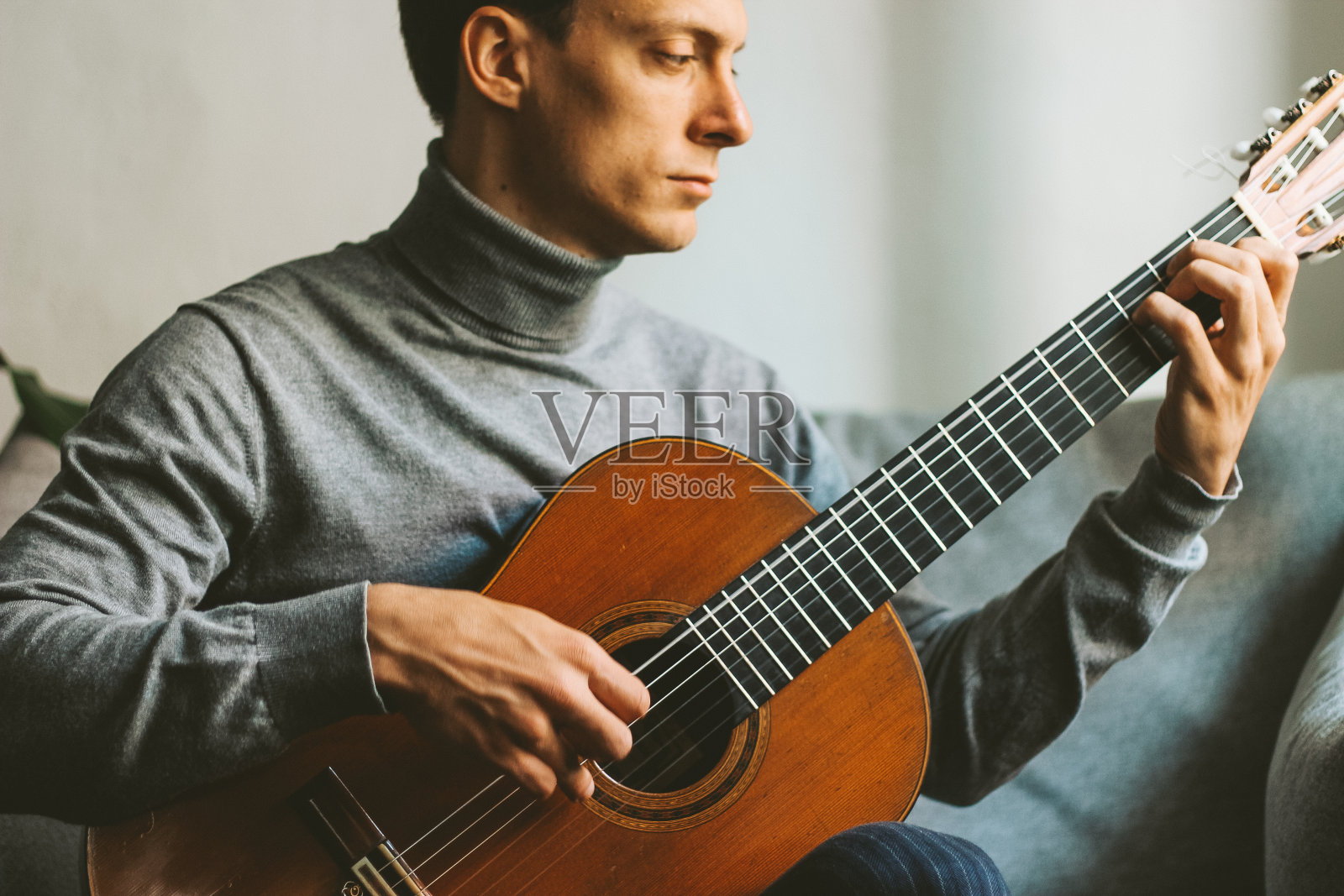 一个年轻人在家里弹吉他照片摄影图片