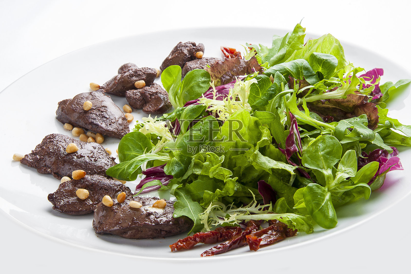 白盘子里有鸡肝和松子的沙拉照片摄影图片