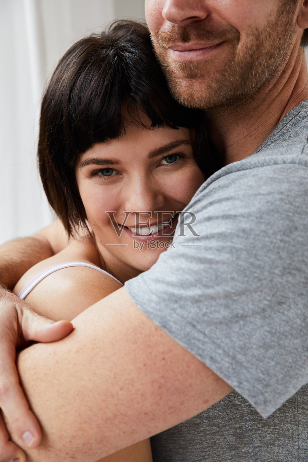 微笑的年轻女子站在她丈夫的怀里照片摄影图片