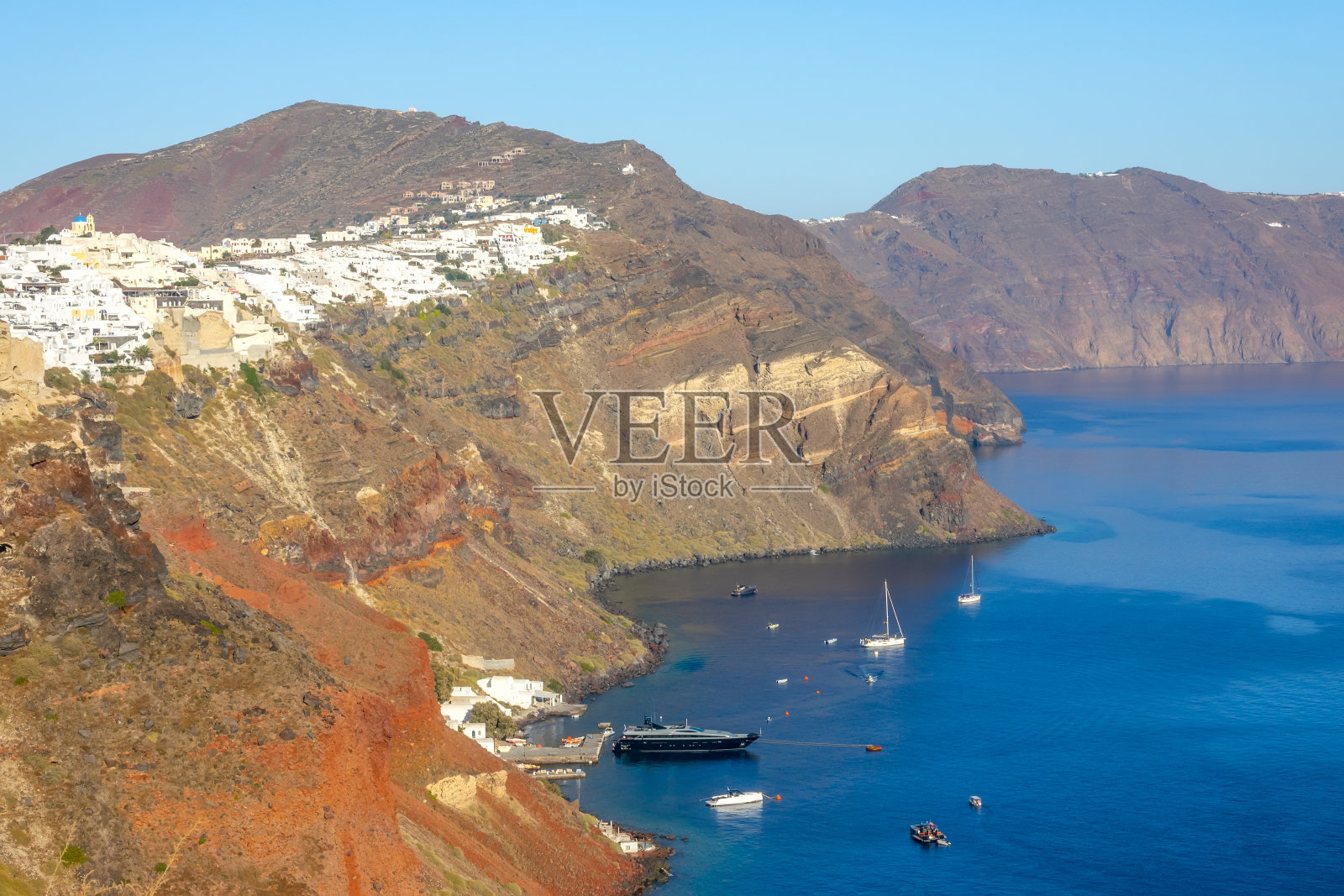 阳光明媚的一天，停泊在圣托里尼岛附近的游艇照片摄影图片