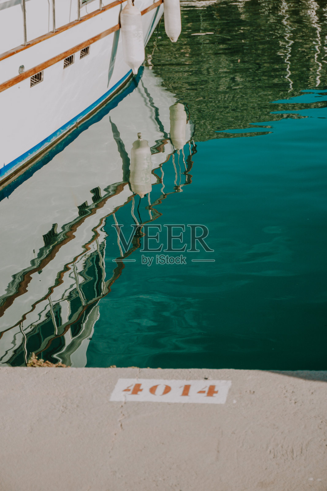 在一个阳光明媚的日子里，一艘船在平坦的港口水域中美丽的倒影。照片摄影图片