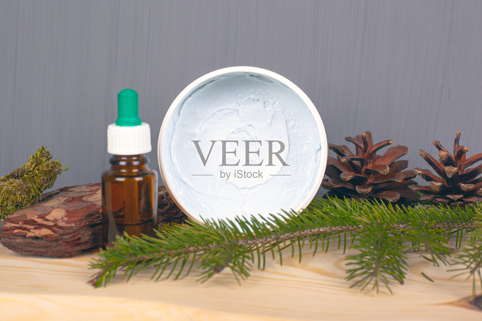 生态身体护理化妆品，身体磨砂膏和精油，松果和树枝在灰色的背景照片摄影图片