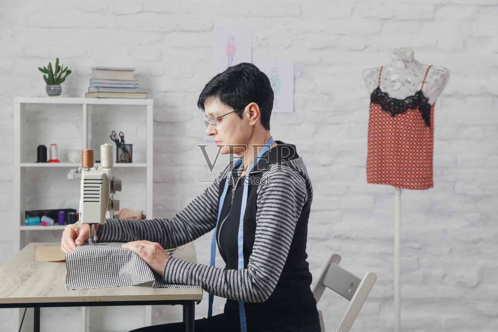 女人在缝纫机上缝制小工作室，时装工作室，慢时尚，裁缝工艺，手工衣服照片摄影图片