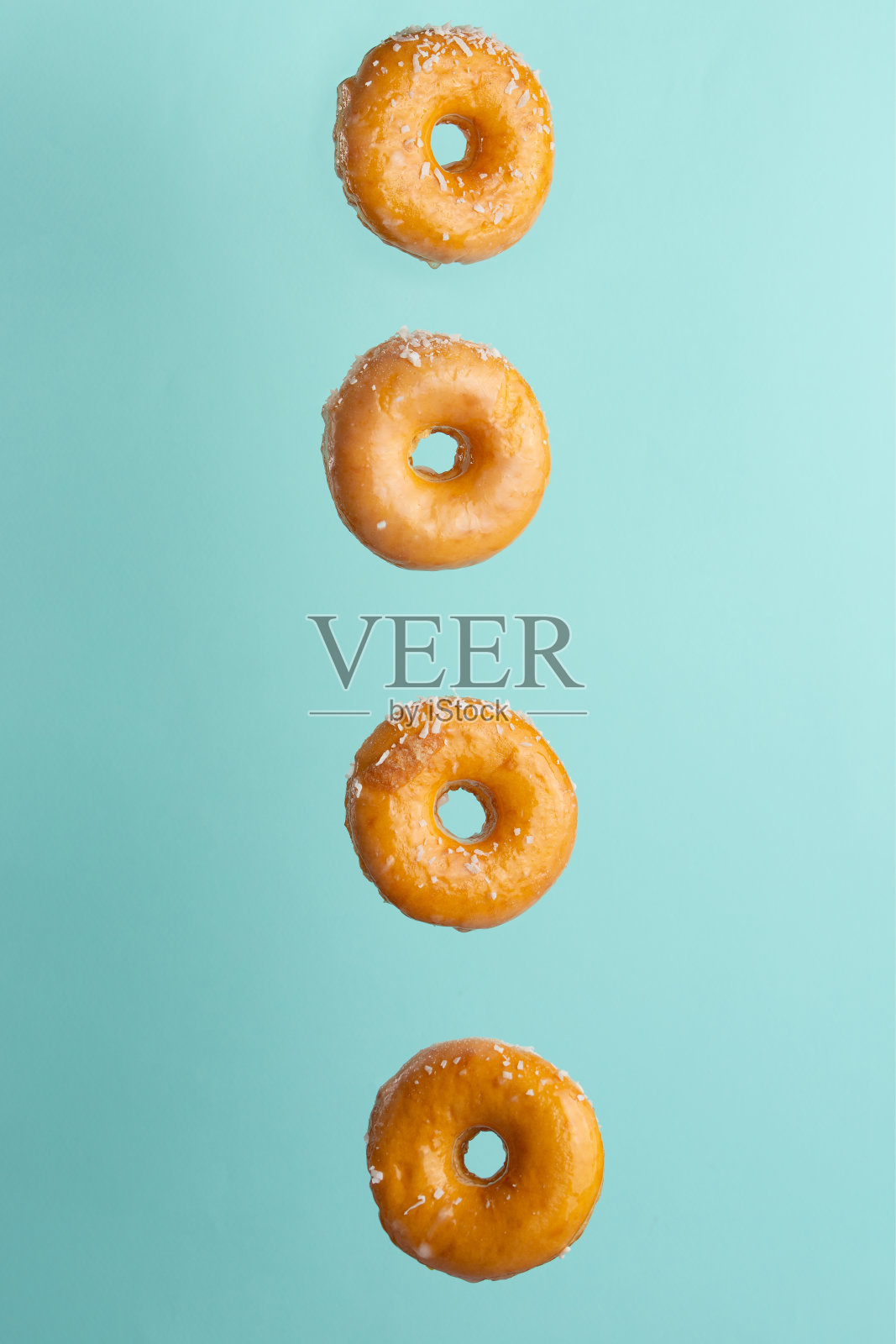 各种装饰的甜甜圈在运动中落在蓝色的背景。照片摄影图片