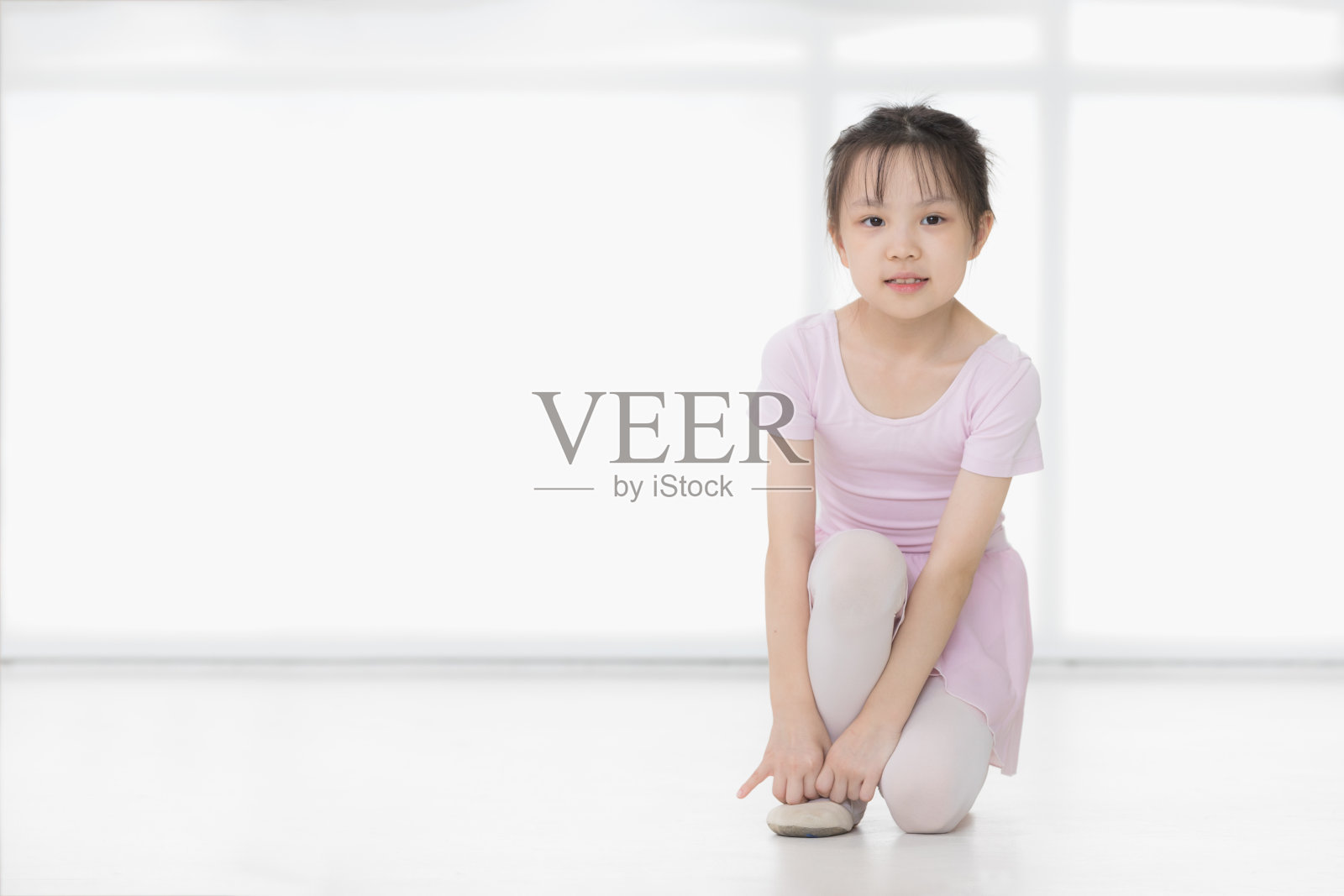 穿着粉色衣服的亚洲女孩摆着芭蕾舞姿势。照片摄影图片