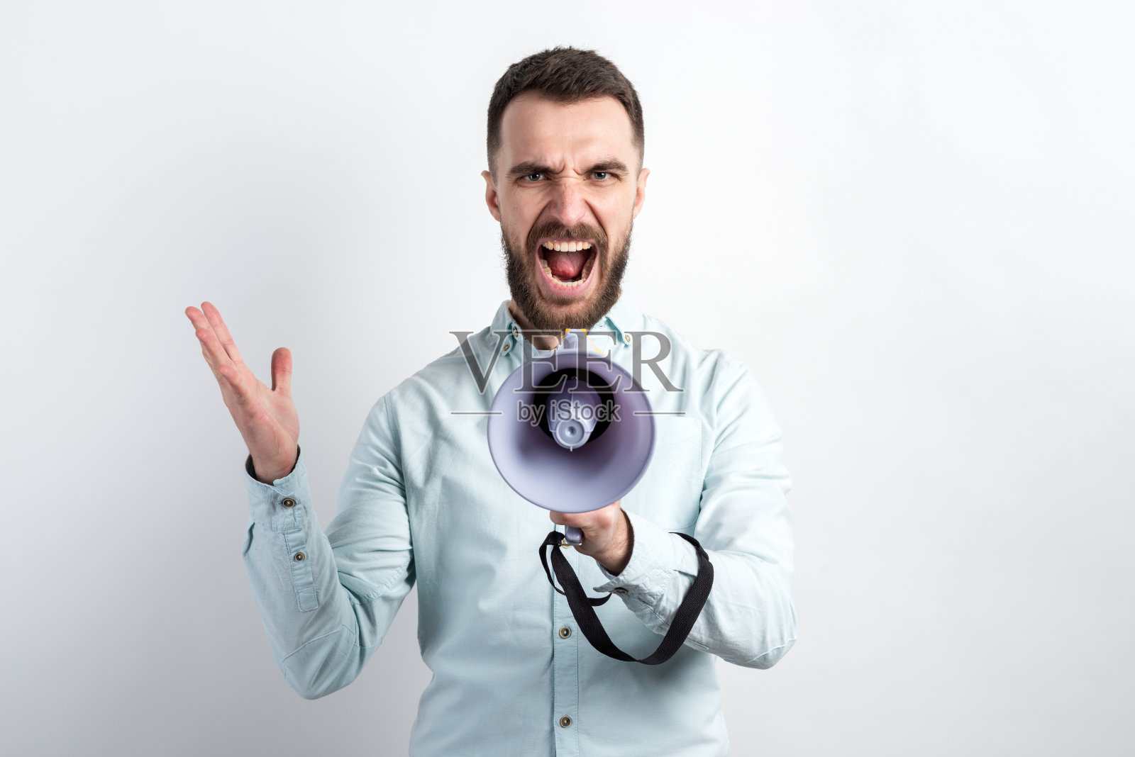 一个男人对着扩音器尖叫的肖像在录音室的白色背景下看着摄像机照片摄影图片