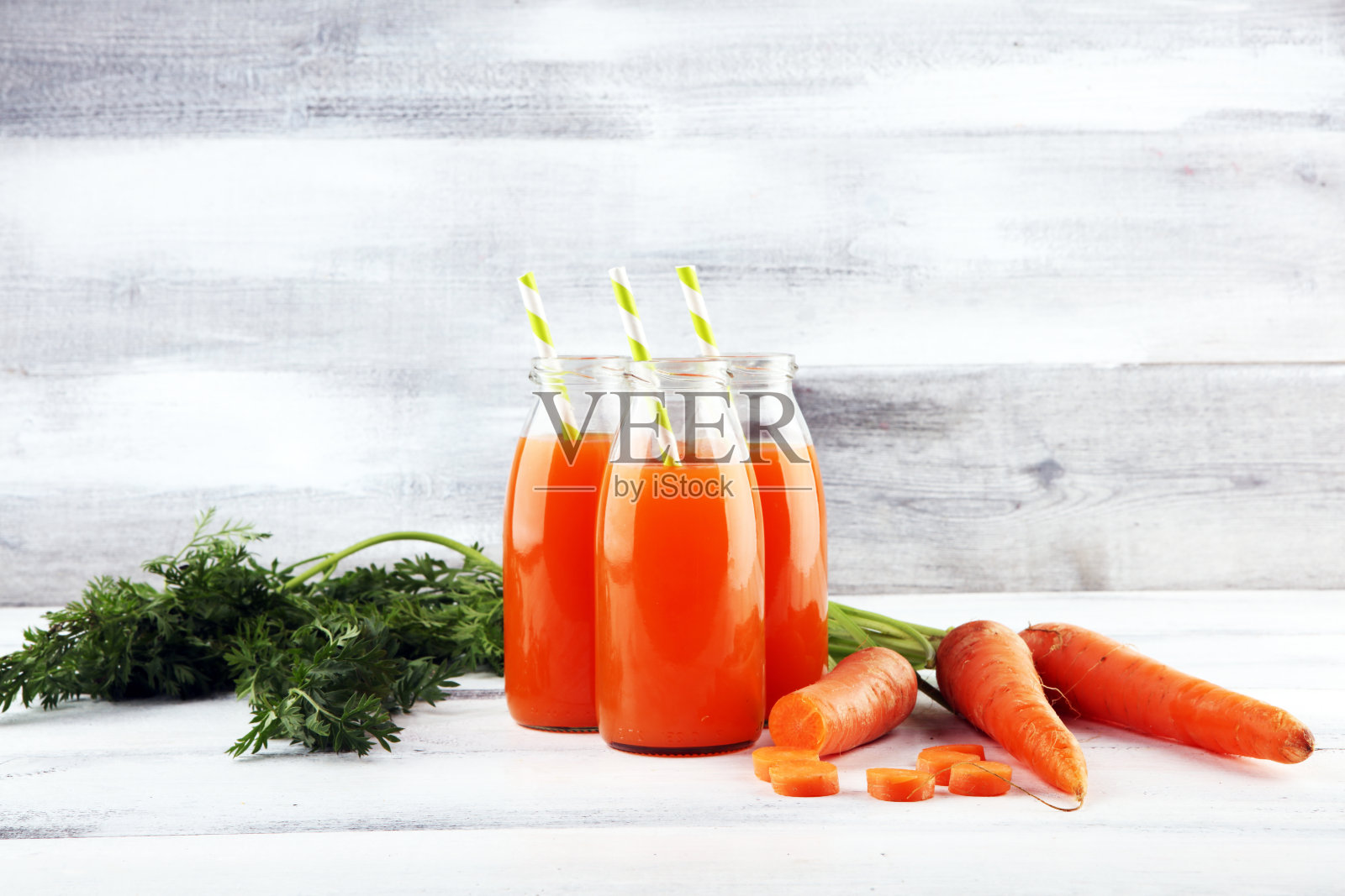 新鲜胡萝卜汁装在瓶子里，桌上放着有机胡萝卜。蔬菜汁集照片摄影图片