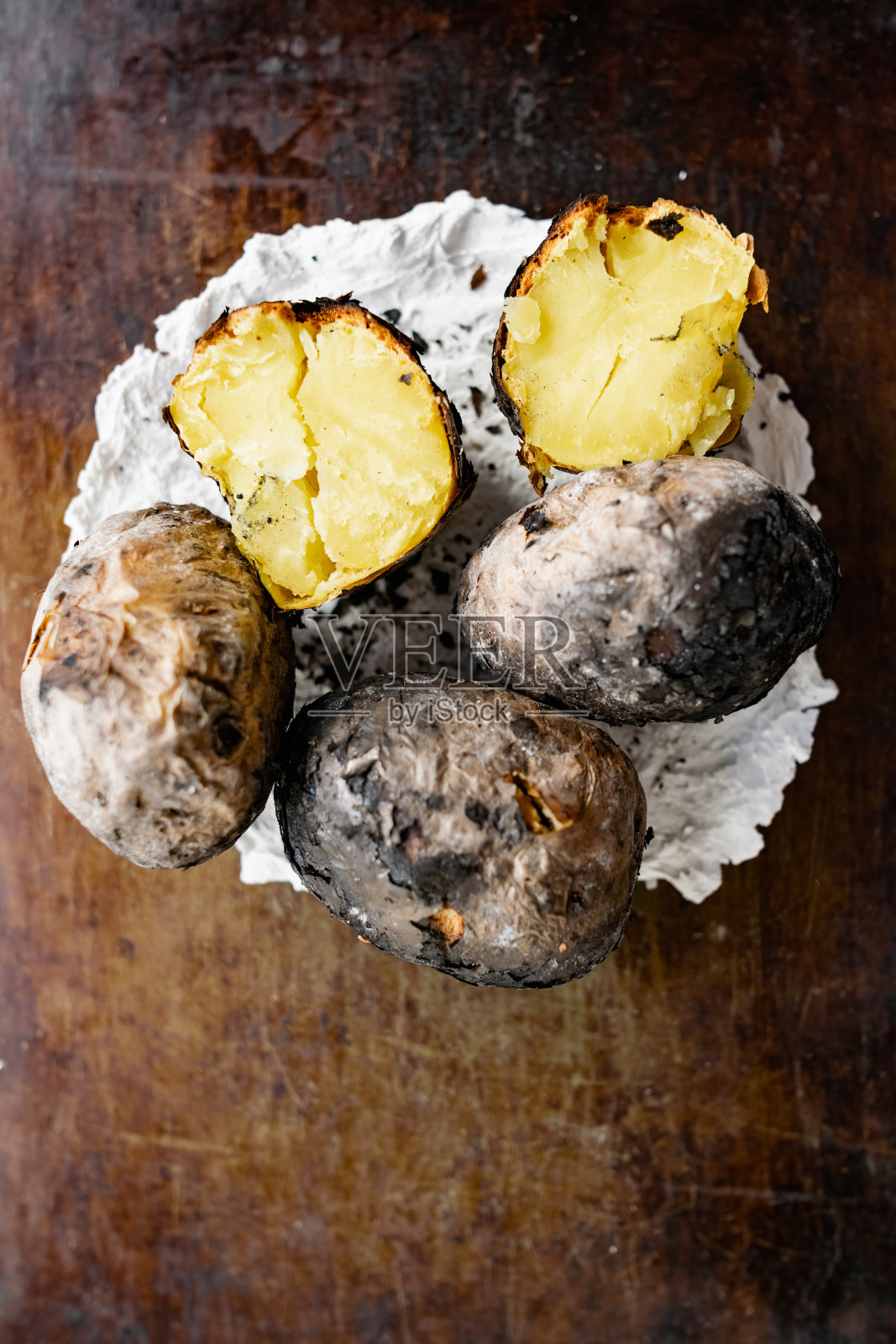 在火上烤土豆的皮按照村里的食谱和方法，直接在灰。照片摄影图片