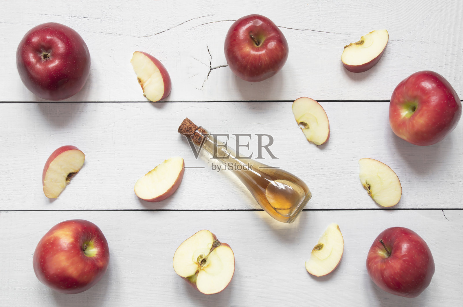 俯视图有机苹果醋玻璃瓶与切片和成熟的新鲜苹果在白色木桌上，健康食品照片摄影图片