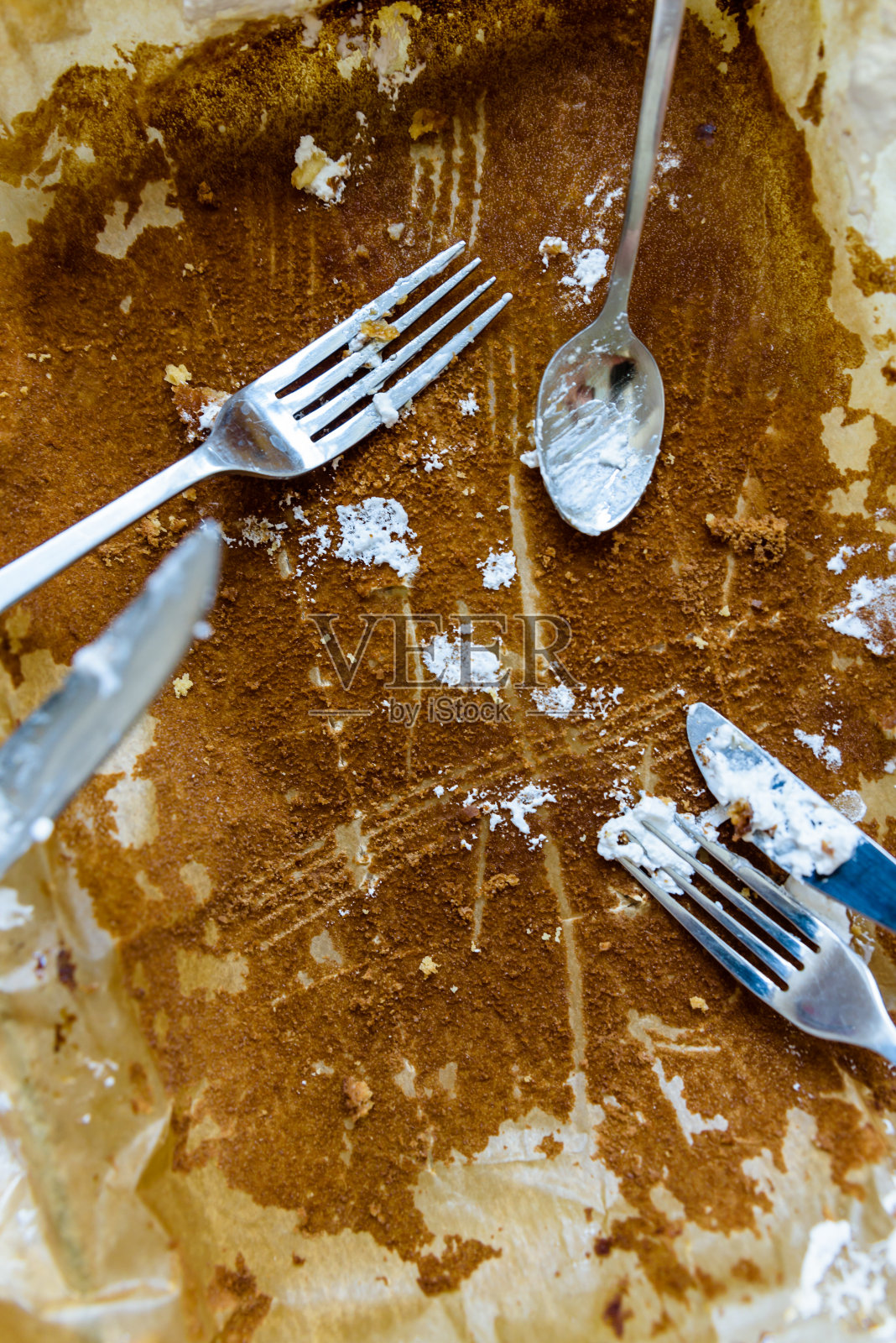 叉子、刀和勺子在空的烤纸盘上覆盖着苹果派糖霜照片摄影图片