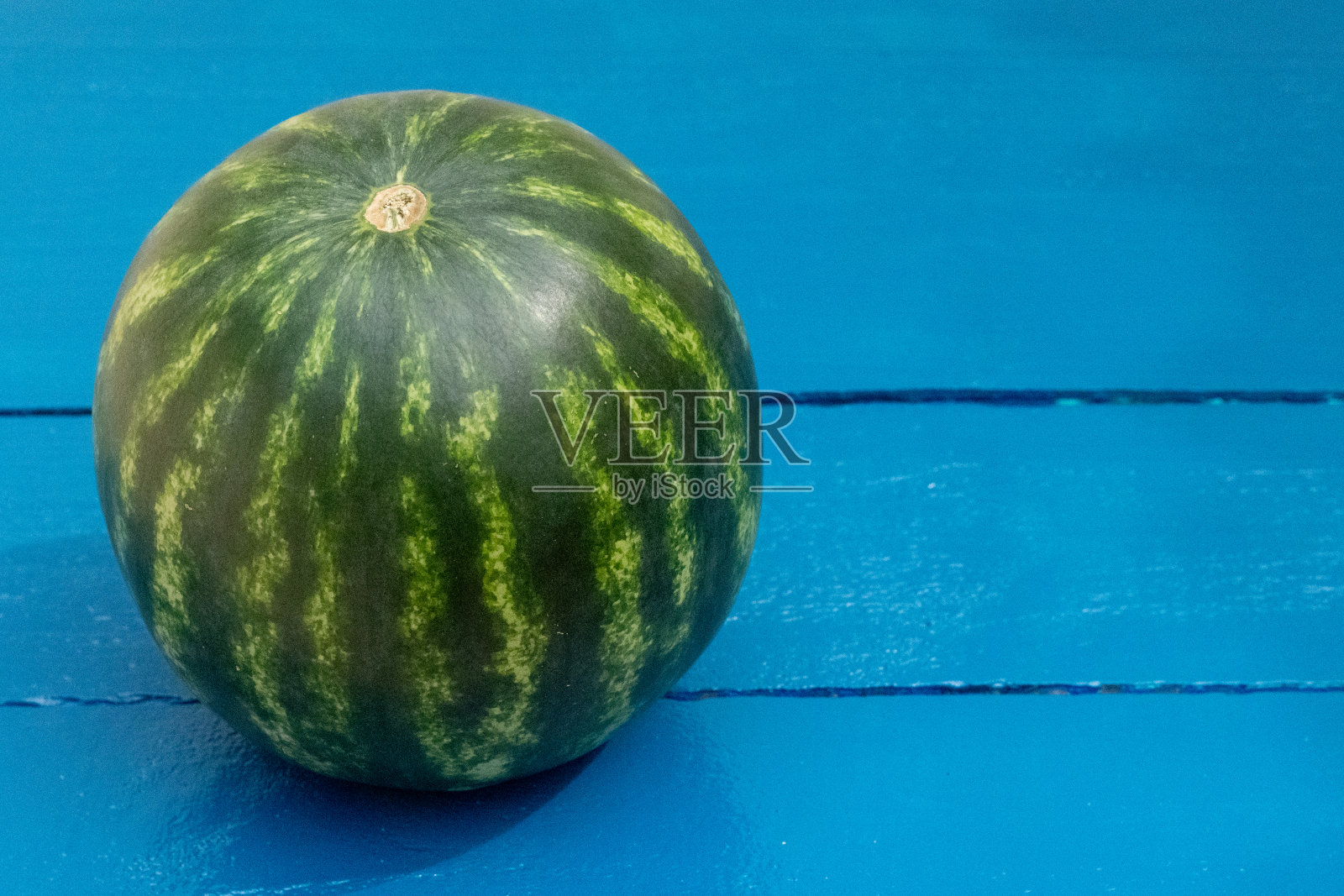 整个切片的小西瓜放在蓝色的木桌上照片摄影图片