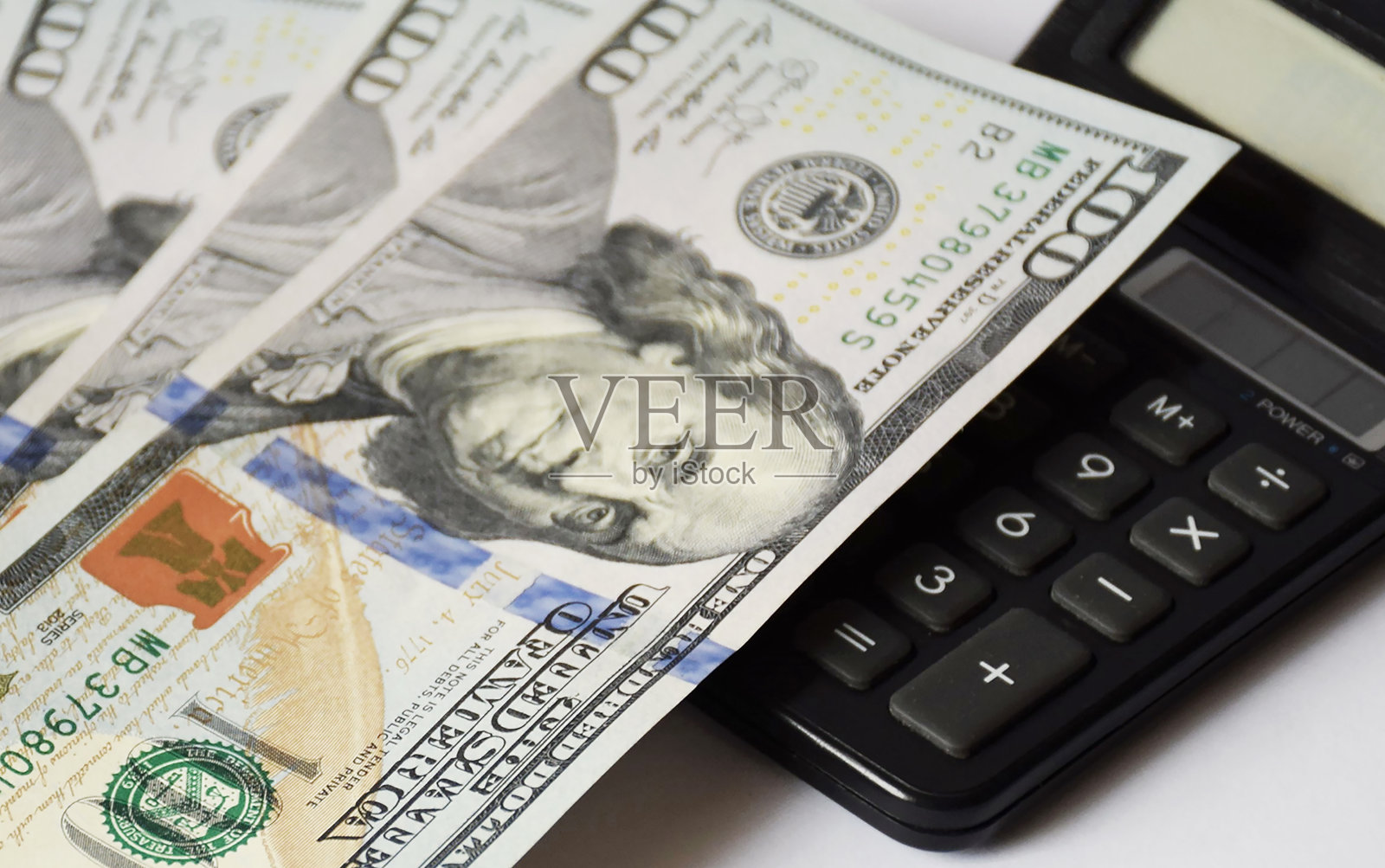 模糊的灯光背景，一堆美元钞票上的白色背景和计算器，商业概念照片摄影图片