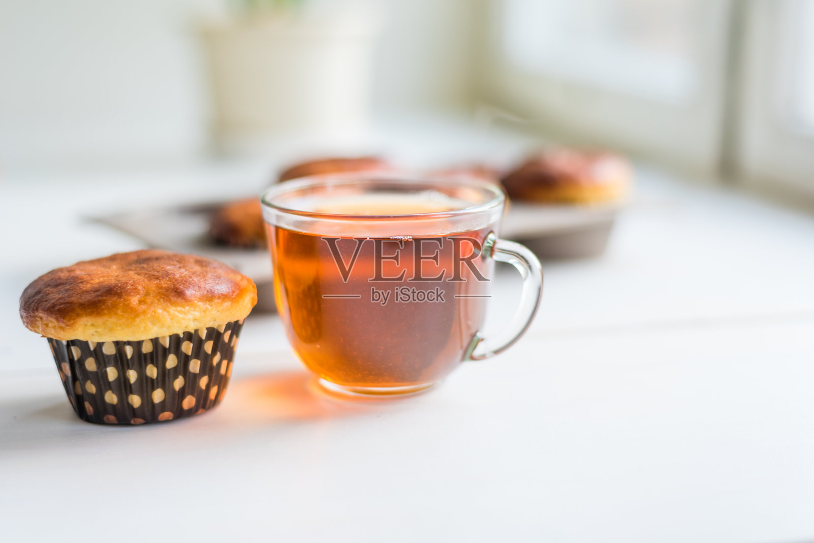 窗边的桌子上放着新鲜美味的自制松饼和一杯早茶照片摄影图片