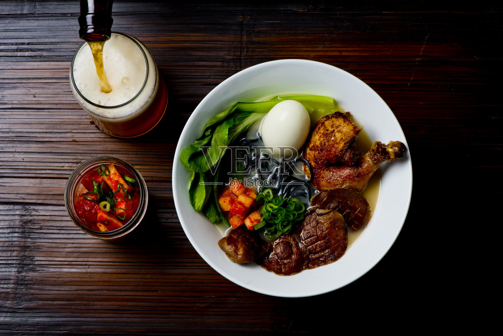 拉面。日式经典汤，有面条，肉汤，猪肉，鸡肉，豆腐，葱，蘑菇，鸡蛋和红辣椒酱。照片摄影图片