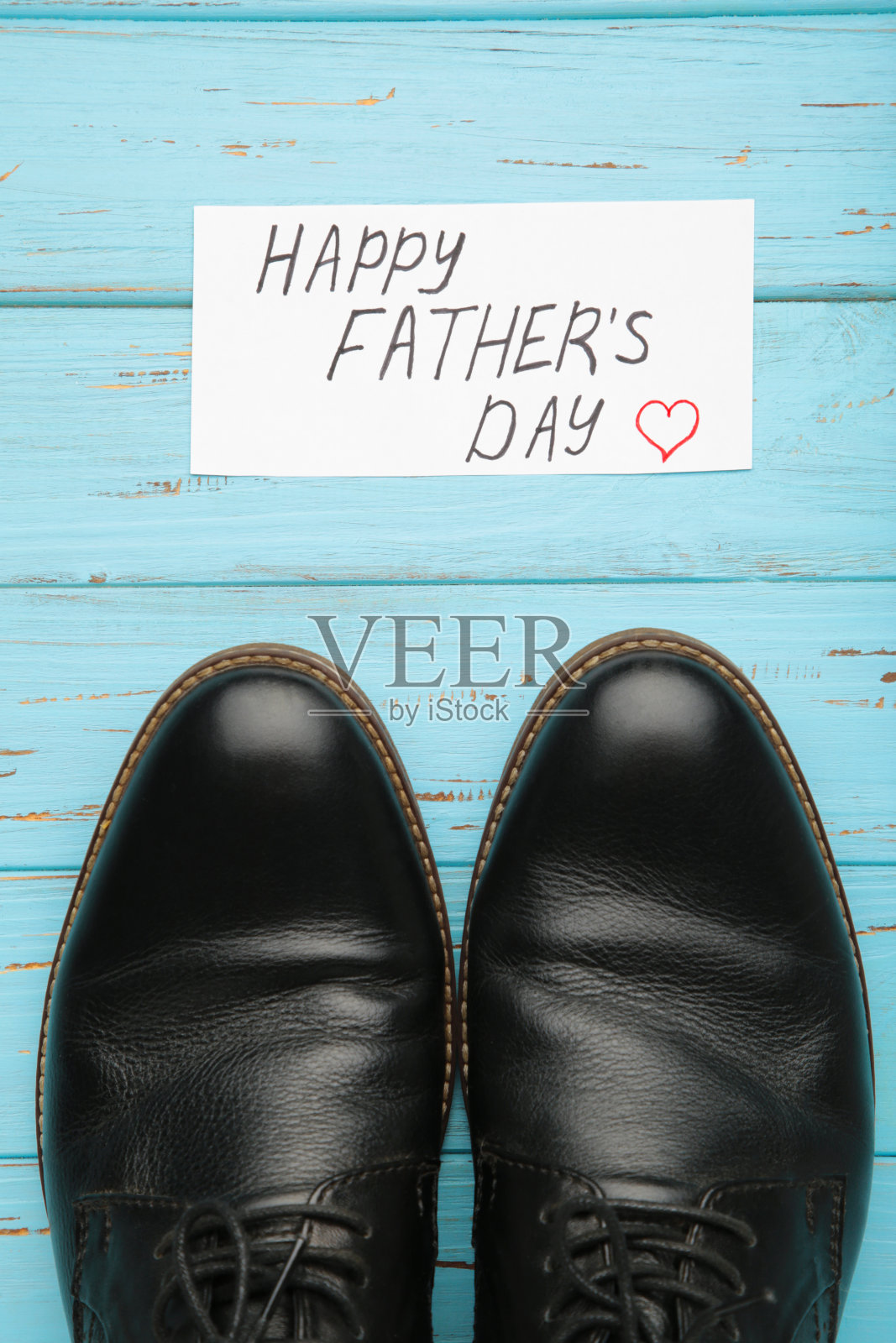 祝你父亲节快乐，蓝色木质背景上的黑色鞋子。照片摄影图片