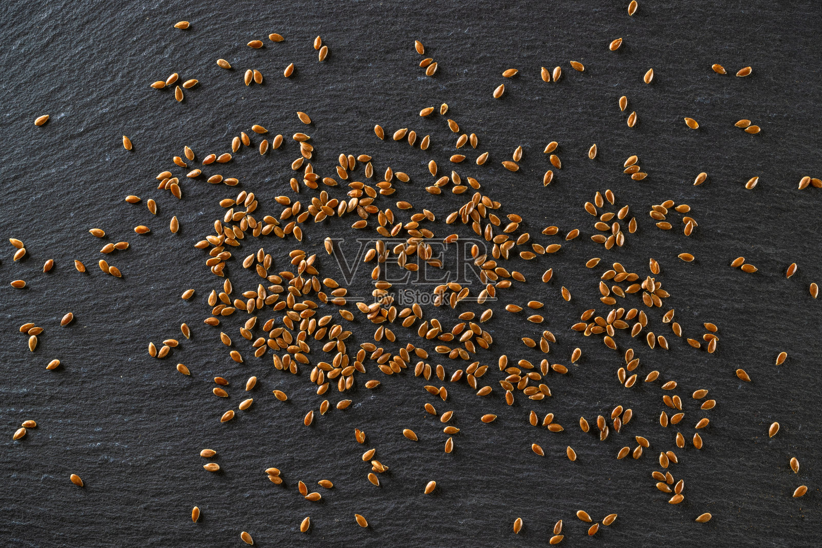 亚麻籽，亚麻籽-有机食品背景。棕色亚麻、亚麻子在木勺中取油孤立深色石头。omega - 3和不饱和脂肪的素食来源。健康食品的概念。照片摄影图片