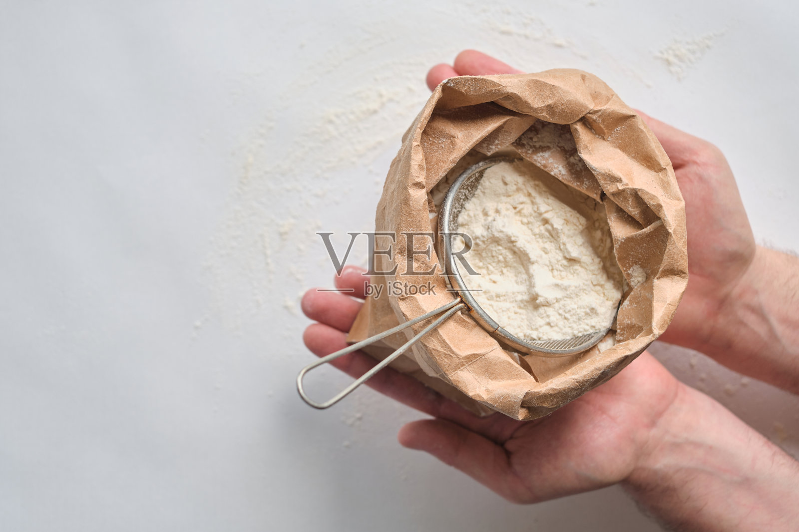 一个人手里拿着一袋面粉。面粉筛。准备烘焙用的面团。为家人做家常菜。厨房里的厨师在做糕点。健康美味的烹饪食谱照片摄影图片