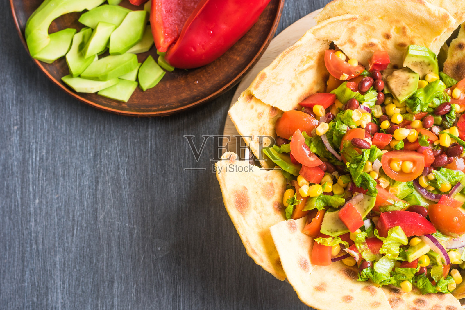 辛辣的墨西哥沙拉配鳄梨，豆子，玉米，洋葱，生菜，辣椒和西红柿，自制玉米饼照片摄影图片