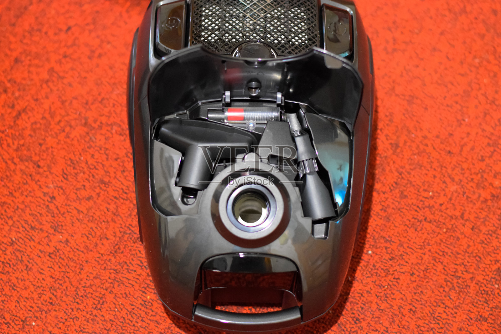 一个带刷子和袋子的吸尘器。红地毯上的吸尘器。照片摄影图片