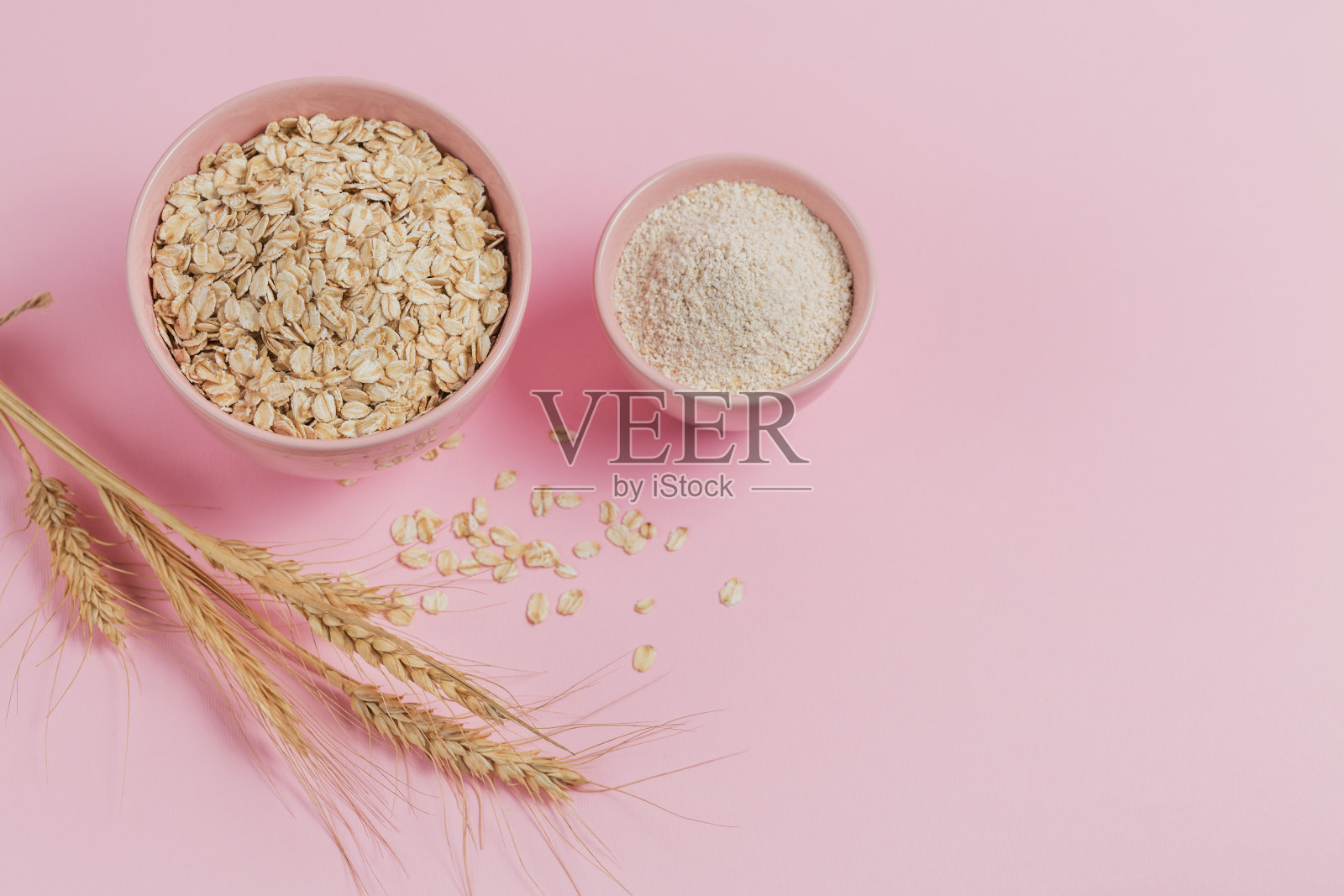 碗干燕麦片，燕麦和小麦穗在光的背景。照片摄影图片