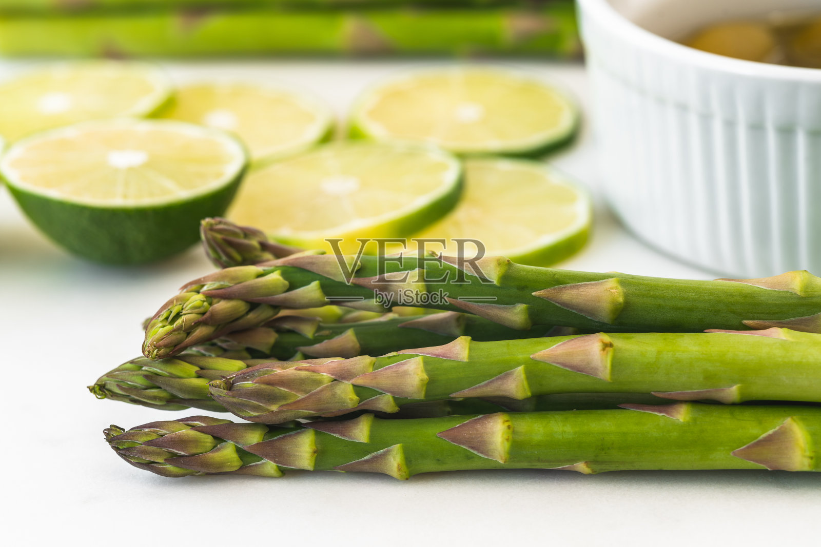 绿色芦笋，柠檬片，橄榄油靠近大理石的服务板，白色的背景照片摄影图片