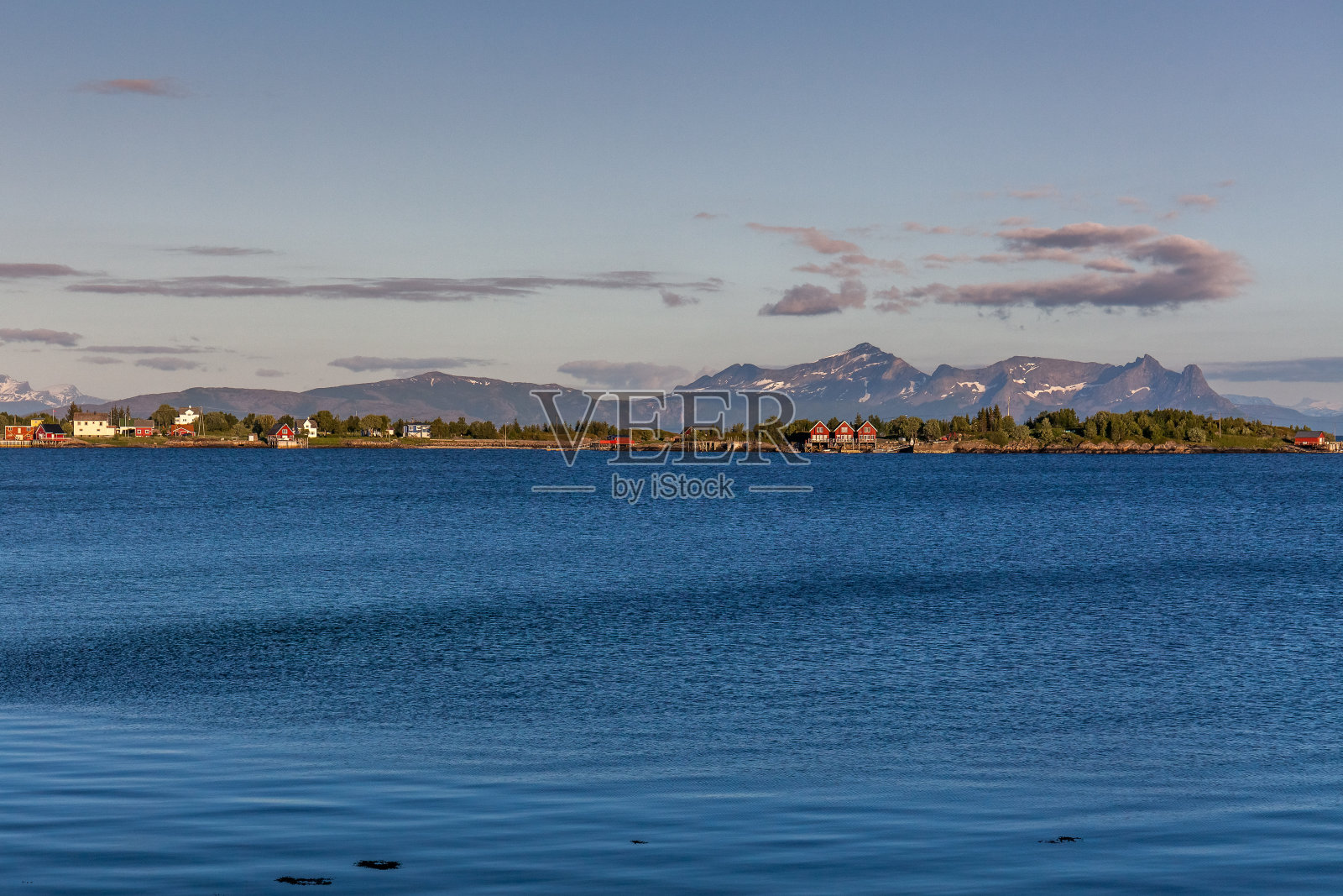 这是挪威的一个神秘峡湾，在极地的日子里，群山和迷雾笼罩在水面上。午夜的太阳，选择性聚焦照片摄影图片