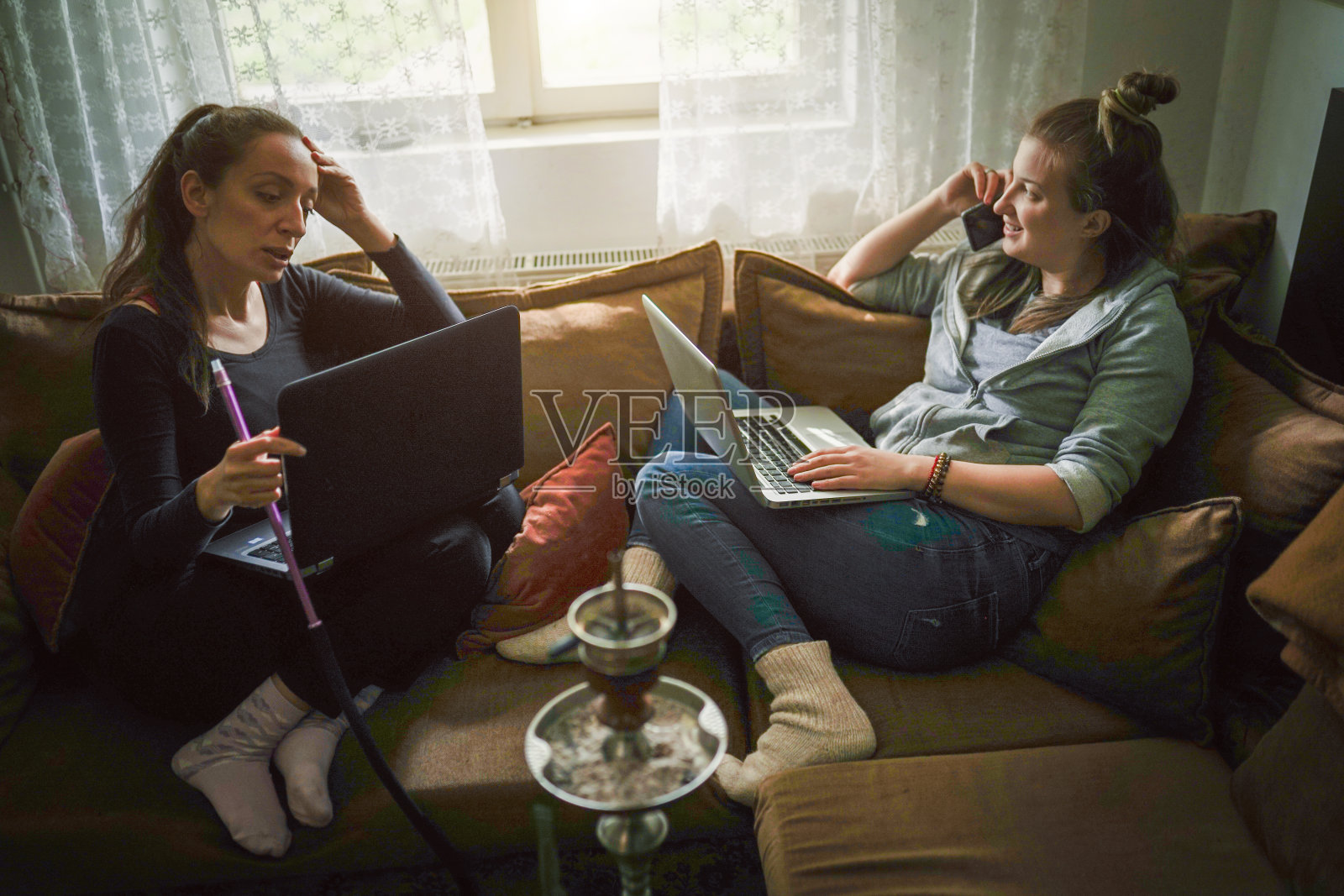 两个年轻的女性朋友在用笔记本电脑照片摄影图片