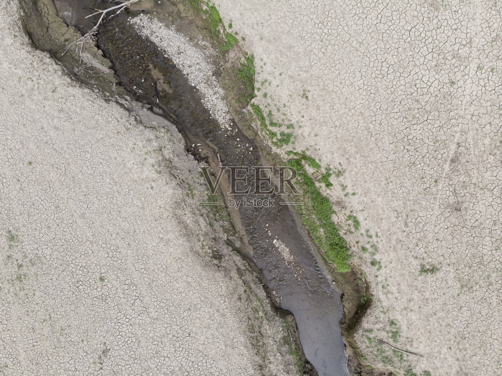 河流穿过干燥、贫瘠、龟裂的土地照片摄影图片