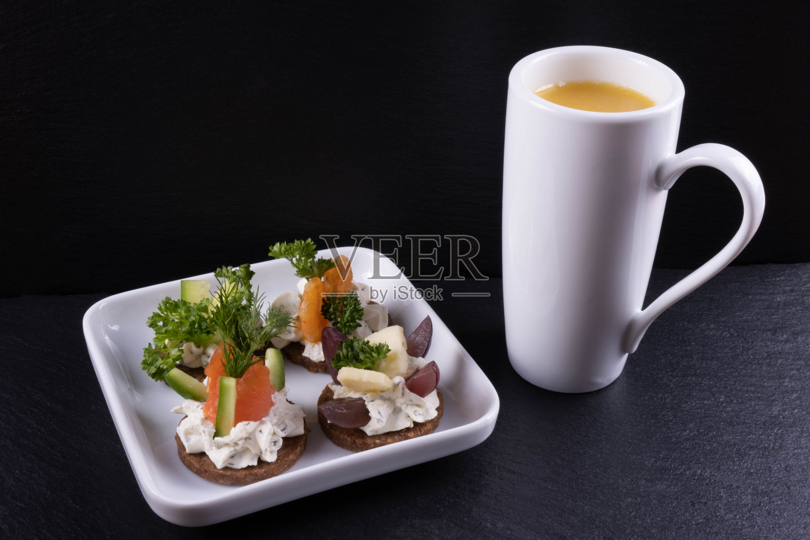 小三明治熏鲑鱼，虾，莳萝和酱汁放在一个盘子里，旁边是橙汁照片摄影图片